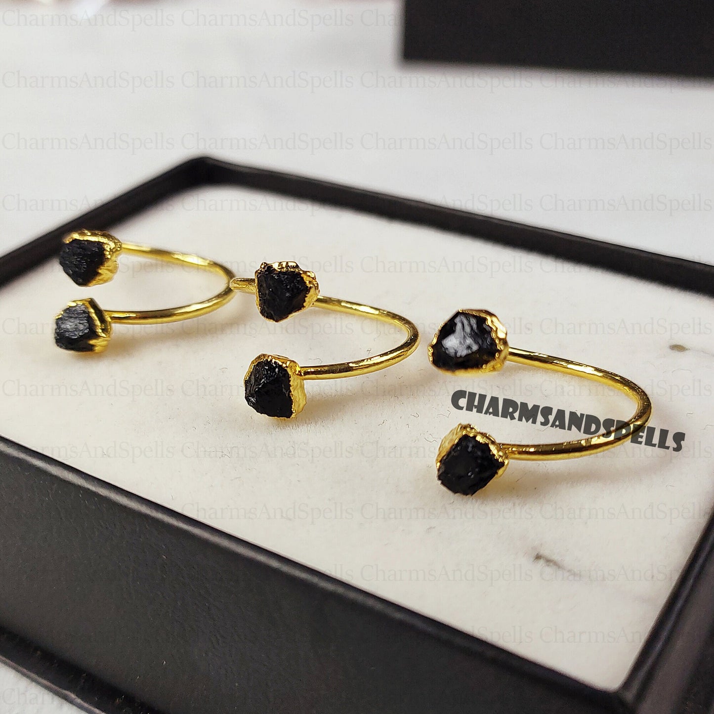 Gold-plated, adjustable rings featuring raw black tourmaline gemstones. The rings showcase the natural, unpolished texture of the black tourmaline crystals. These unique, handmade gemstone rings are ideal as protection jewelry, unique gifts for women, or a statement piece for bohemian, spiritual, or earthy styles. The black tourmaline offers grounding and protective energies. These electroplated raw black tourmaline rings are perfect for those seeking a raw crystal and metaphysical benefits.