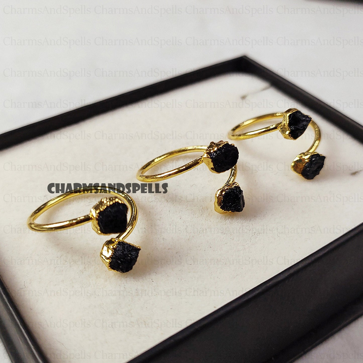 Gold-plated, adjustable rings featuring raw black tourmaline gemstones. The rings showcase the natural, unpolished texture of the black tourmaline crystals. These unique, handmade gemstone rings are ideal as protection jewelry, unique gifts for women, or a statement piece for bohemian, spiritual, or earthy styles. The black tourmaline offers grounding and protective energies. These electroplated raw black tourmaline rings are perfect for those seeking a raw crystal and metaphysical benefits.