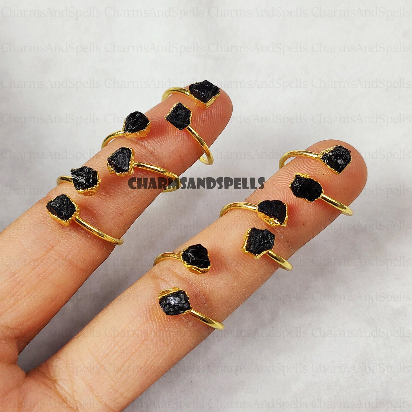Gold-plated, adjustable rings featuring raw black tourmaline gemstones. The rings showcase the natural, unpolished texture of the black tourmaline crystals. These unique, handmade gemstone rings are ideal as protection jewelry, unique gifts for women, or a statement piece for bohemian, spiritual, or earthy styles. The black tourmaline offers grounding and protective energies. These electroplated raw black tourmaline rings are perfect for those seeking a raw crystal and metaphysical benefits.