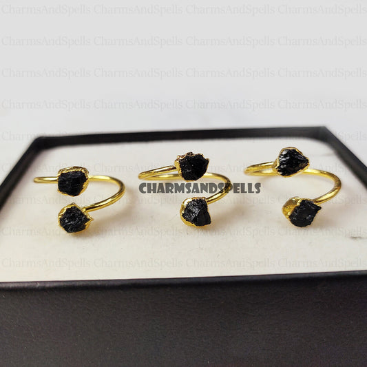Gold-plated, adjustable rings featuring raw black tourmaline gemstones. The rings showcase the natural, unpolished texture of the black tourmaline crystals. These unique, handmade gemstone rings are ideal as protection jewelry, unique gifts for women, or a statement piece for bohemian, spiritual, or earthy styles. The black tourmaline offers grounding and protective energies. These electroplated raw black tourmaline rings are perfect for those seeking a raw crystal and metaphysical benefits.
